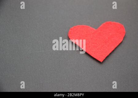 Red felt heart on dark brown background. Love concept Stock Photo