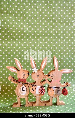 Three wooden Easter bunnies with painted decoration and the text Easter written on eggs. Stock Photo