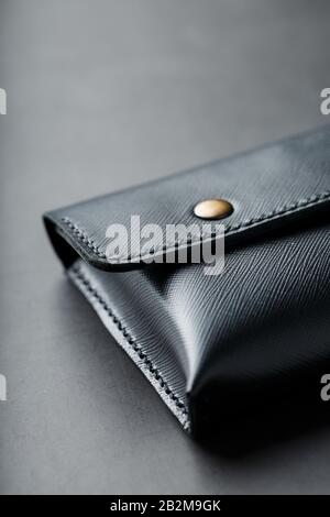 Black wallet made of genuine leather on a dark background. Handmade leather items. Rivets and seam close up Stock Photo