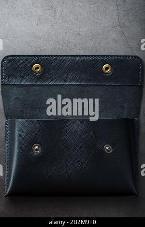 Black wallet made of genuine leather on a dark background. Handmade leather items. Rivets and seam close up Stock Photo