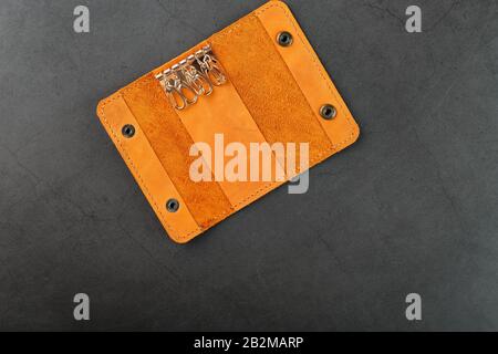 Key wallet made of genuine brown nubuck leather on a dark background. Handmade leather items. Handmade rivets and seam closeup Stock Photo