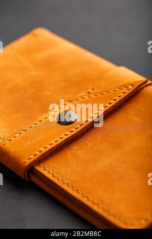 Wallet made of genuine brown nubuck leather on a dark background. Handmade leather items. Handmade rivets and seam closeup Stock Photo