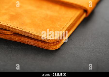 Wallet made of genuine brown nubuck leather on a dark background. Handmade leather items. Handmade rivets and seam closeup Stock Photo