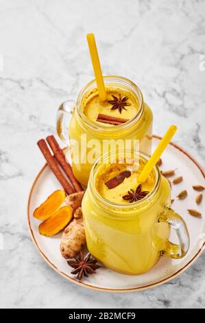 Hadi Doodh know as Golden Turmeric Milk in Mason Jar on white marble background. Golden Milk is ayurvedic recipe of hot milk with turmeric, ginger and Stock Photo