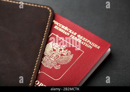Brown leather cover with a red passport on a dark background. Russian Federation, handwork close-up. Stock Photo