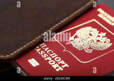 Brown leather cover with a red passport on a dark background. Russian Federation, handwork close-up. Stock Photo
