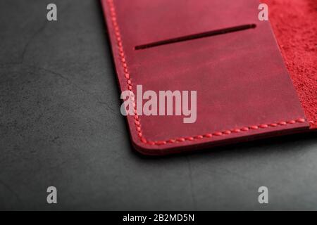 Red leather cover for a passport on a dark background. Genuine leather, handmade, close up stitching. Close-up Stock Photo