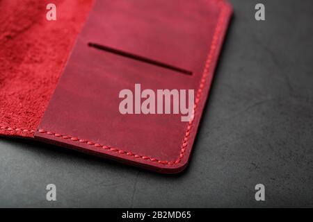 Red leather cover for a passport on a dark background. Genuine leather, handmade, close up stitching. Close-up Stock Photo