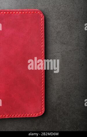 Red leather cover for a passport on a dark background. Genuine leather, handmade, close up stitching. Close-up Stock Photo