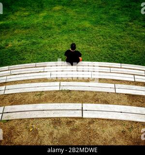 Lonely man sitting on bleachers. Back view Stock Photo
