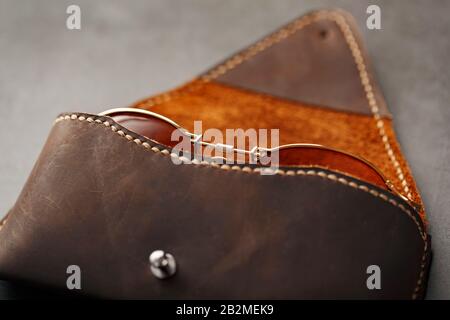 Genuine brown leather glasses case, handmade on a dark background. Glasses inside the case. Close-up Stock Photo