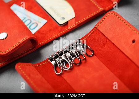 Set of key holder wallet with money and electronic cards and a key holder made of genuine red leather, handmade on a dark background. Close-up Stock Photo