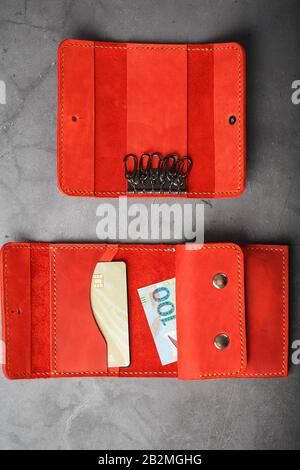 Set of key holder wallet with money and electronic cards and a key holder made of genuine red leather, handmade on a dark background. Close-up Stock Photo