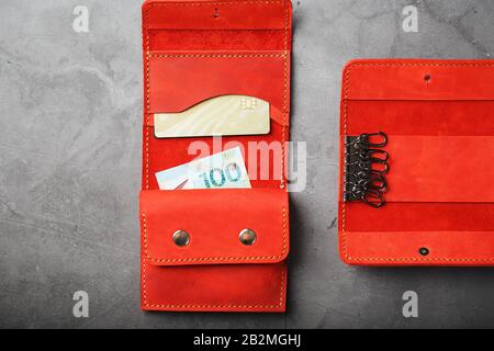 Set of key holder wallet with money and electronic cards and a key holder made of genuine red leather, handmade on a dark background. Close-up Stock Photo
