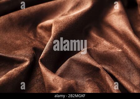 Brown velor textural background pattern. Gorgeous elastic velor fabric has a velvet pile, shine and texture. Volumetric background of velor fabric. Stock Photo