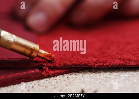 A leather craftsman works with leather. Sews leather goods. Making things handmade. Women's hands with a needle, thread, scissors and a blowtorch. Clo Stock Photo