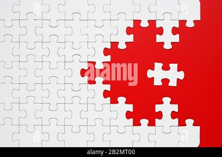 White puzzle pieces on a red background separated. Puzzle arrow, concept of the direction and destruction of the puzzle Concept for business Stock Photo