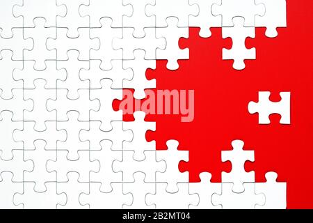 White puzzle pieces on a red background separated. Puzzle arrow, concept of the direction and destruction of the puzzle Concept for business Stock Photo