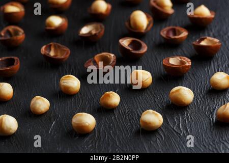 Purified and shell repeats macadamia nuts on black textural stone background. Healthy eating concept. The most expensive nut in the world, growing in Stock Photo