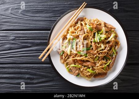 Tasty stir-fried Chinese egg noodles with napa cabbage green onions and pork closeup in a plate on the table Horizontal top view from above Stock Photo