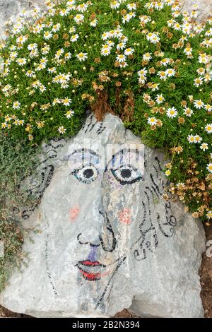 Face painted on rock in city park. Stock Photo