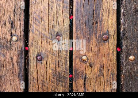 Wooden planks attached with rusty screws and red seeds outdoors, closeup Stock Photo