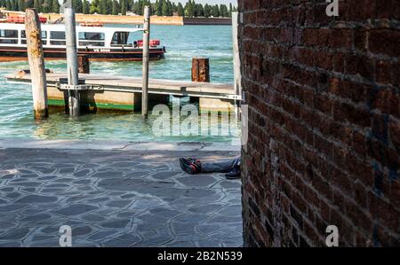 Homeless man asleep on the floor, no face showing, Venice, italy Stock Photo