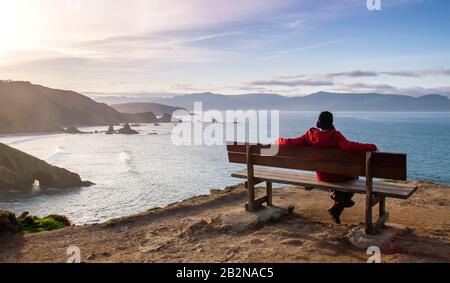 Man relaxing on a woden bench in Loiba Cliffs, Ortigueira, Spain Stock Photo