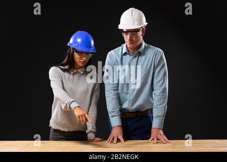Caucasian male and mixed race female architects on black background Stock Photo