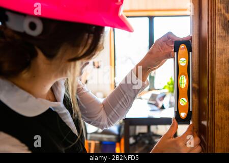 selective focus view of spirit level measuring instrument on woman's hands. female construction inspector during house inspection and quality control Stock Photo
