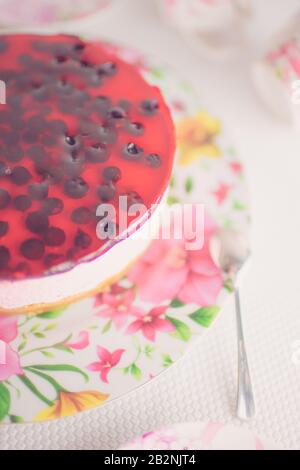 Floral dish with red currant cheesecake and spoon on the white table Stock Photo