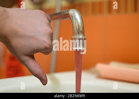 dirty rusty water flows from a chrome faucet Stock Photo