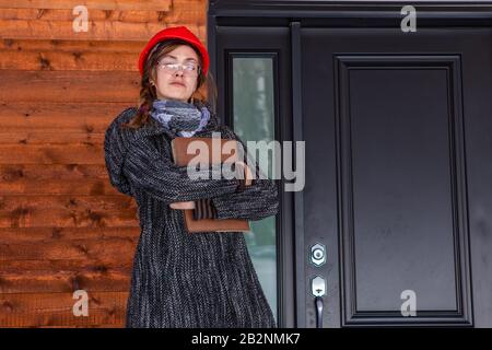 low angle portrait of construction inspector woman with confident look standing outdoor next to a house entrance and holding a clipboard. Stock Photo