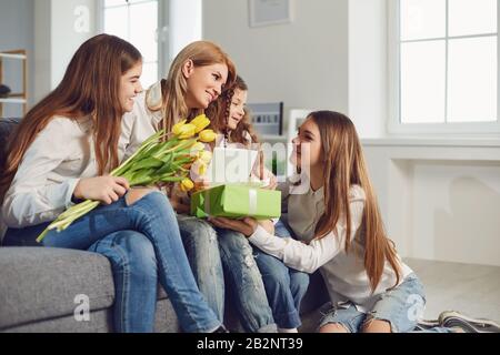 Happy Mother's Day. Children daughters give mom a bouquet of flowers at home. Stock Photo