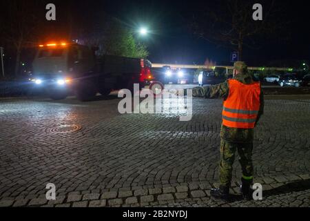 03 March 2020, Saxony-Anhalt, Burg: A soldier from Logistics Battalion 171 shows US Army vehicles the way out of the Clausewitz Gate Barracks. The military vehicle will be transferred from a depot in Belgium to Poland for the US-led exercise 'Defender Europe 2020'. On their way through Saxony-Anhalt the military convoys stop at the Clausewitz barracks to refuel. Around 37,000 soldiers from 18 nations will participate in the exercise. In the coming weeks, the US military is moving around 1,500 vehicles to Poland, which are to be refuelled in the Clausewitz barracks. Photo: Klaus-Dietmar Gabbert Stock Photo