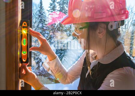 close up on construction inspector woman using torpedo spirit level to measuring an interior vertical surface next to a window. air quality inspection Stock Photo