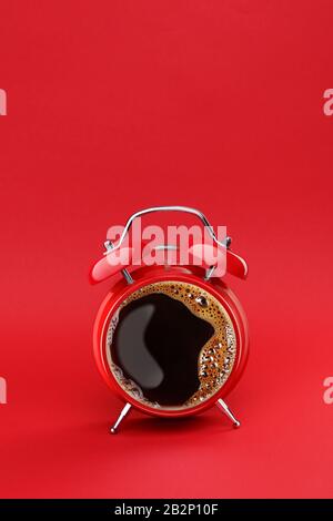 Morning coffee. Coffee time concept. Coffee break. Vintage red twin bell alarm clock with cup of coffee isolated on red background. Copy space Stock Photo