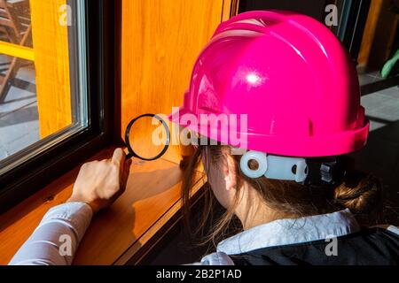 close up on woman inspector using a magnifying glass during air quality inspection, looking for molds or fungi problems on the wooden window edges Stock Photo