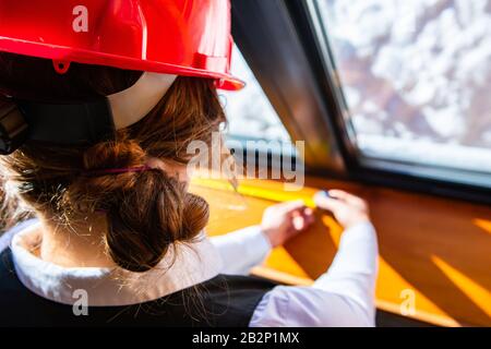 close up on female construction inspector wearing red hard hat as she checking the window using a tape measure, inspecting eco energy efficient home. Stock Photo