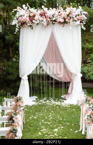 Wedding arch decorated with flowers outdoors. Beautiful wedding set up. Wedding ceremony in the garden Stock Photo