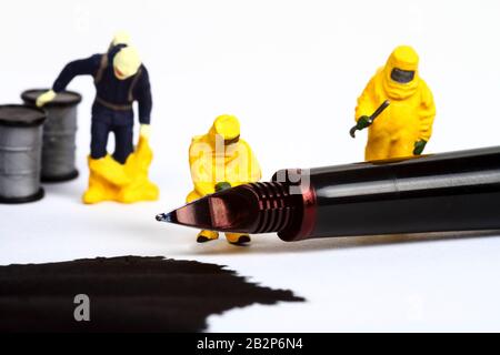 Conceptual image of miniature figure people wearing hazmat suits inspecting a fountain pen and spilled ink Stock Photo