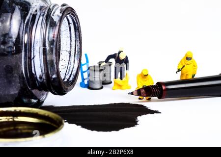 Conceptual image of miniature figure people wearing hazmat suits inspecting a fountain pen and spilled ink Stock Photo