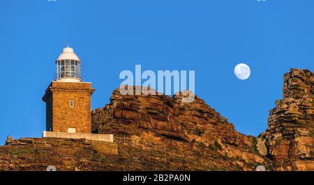 Lighthouse Cape of Good hope and moon in blue sky. South Africa. Stock Photo