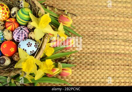 Happy Easter - painted eggs and daffodils on colored background Stock Photo