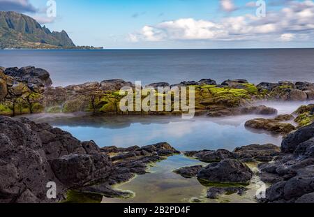 Long exposure of the calm waters of Queen's Bath, a rock pool off Princeville on north shore of Kauai Stock Photo
