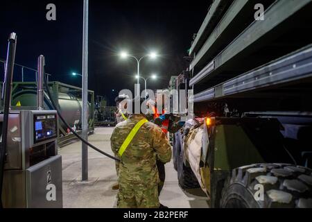 03 March 2020, Saxony-Anhalt, Burg: A soldier of Logistics Battalion 171 refuels a US Army vehicle in Clausewitz Barracks with the driver standing next to the German soldier. The military vehicle will be transferred from a depot in Belgium to Poland for the US-led exercise 'Defender Europe 2020'. On their way through Saxony-Anhalt the military convoys stop at the Clausewitz barracks to refuel. Around 37,000 soldiers from 18 nations will participate in the exercise. In the coming weeks, the US military is moving around 1,500 vehicles to Poland, which are to be refuelled in the Clausewitz barrac Stock Photo