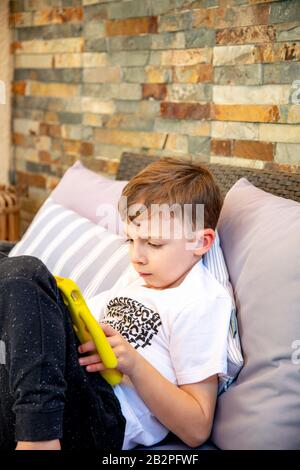 Six year old boy in garden on tablet. Stock Photo