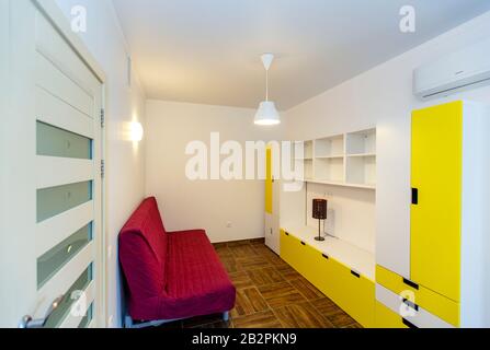 Children's room in the cottage. Bunk bed, window with blue curtains, large wardrobe with yellow doors. Stock Photo