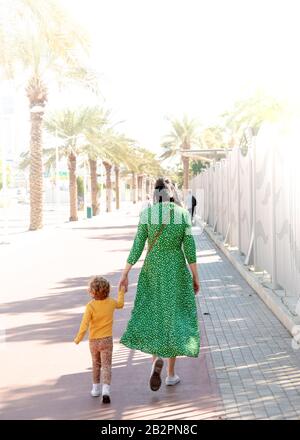 Colour image of mother and child hand in hand along walkway Stock Photo