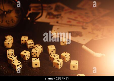 Dice,cigarettes, cards, and an abandoned alarm clock on a table in an underground casino Stock Photo